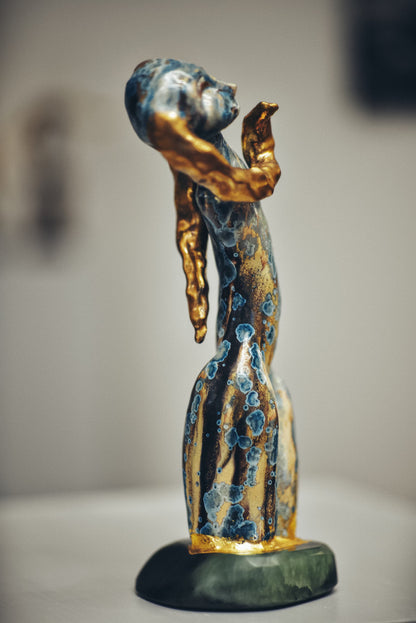 Decorative figurine with gold and blue accents on a plain background