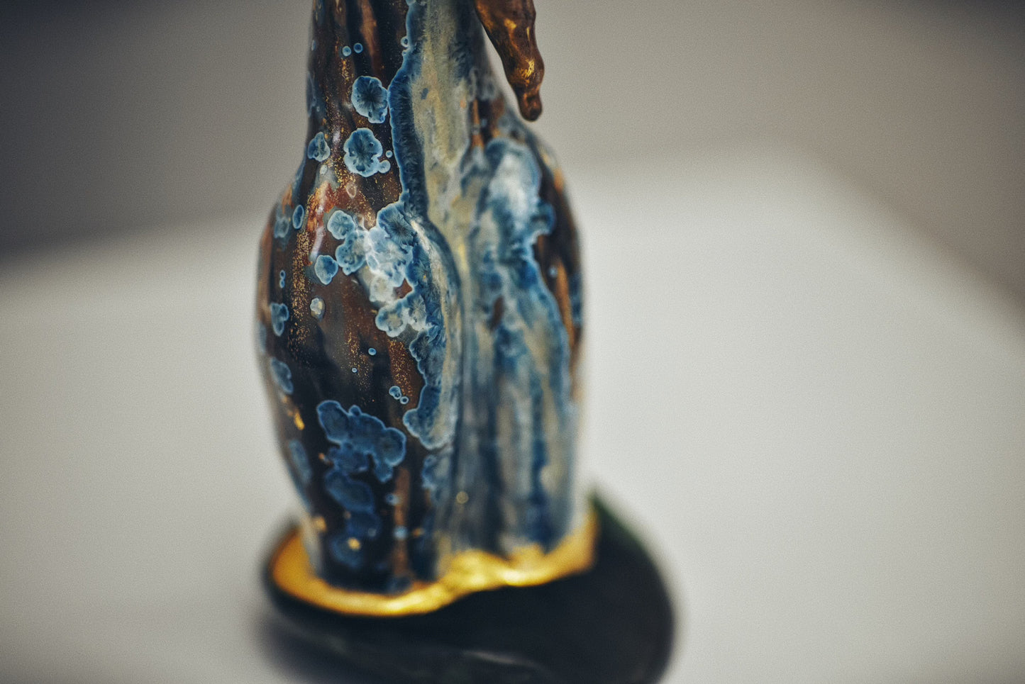 Decorative figurine with blue and gold patterns on a plain background