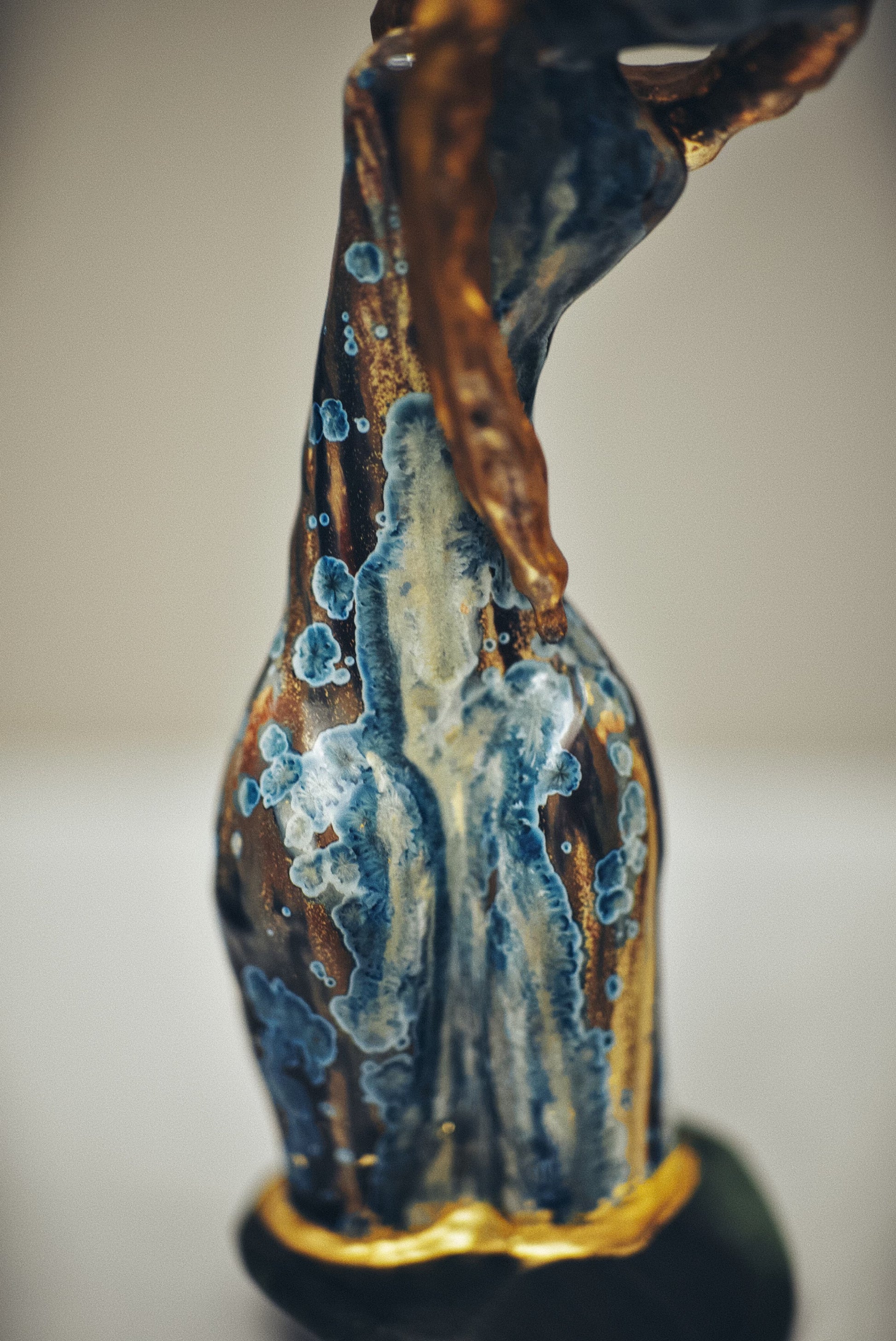 Decorative statue with blue and gold glaze on a neutral background