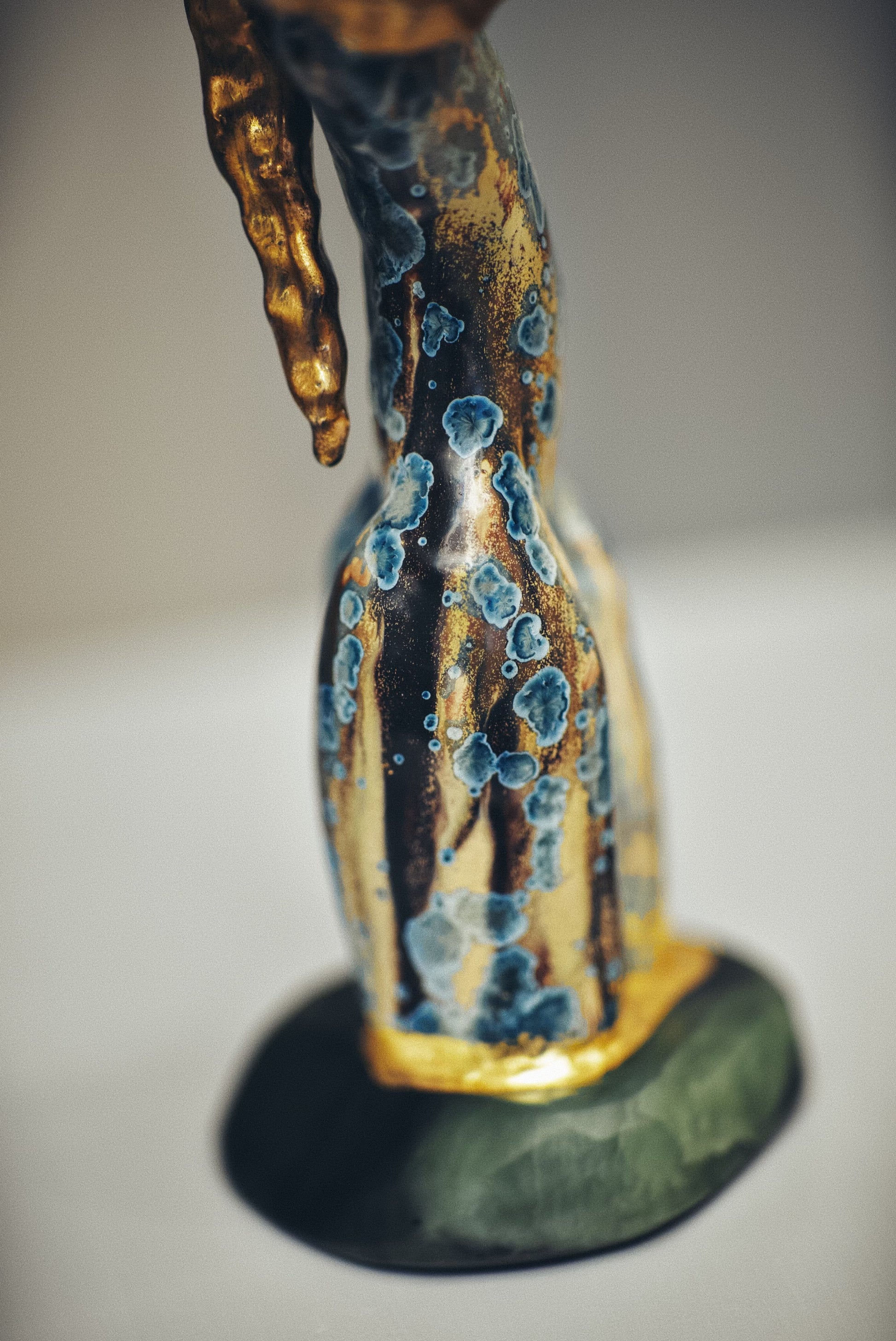 Decorative ceramic figure with blue and gold glaze on a plain background