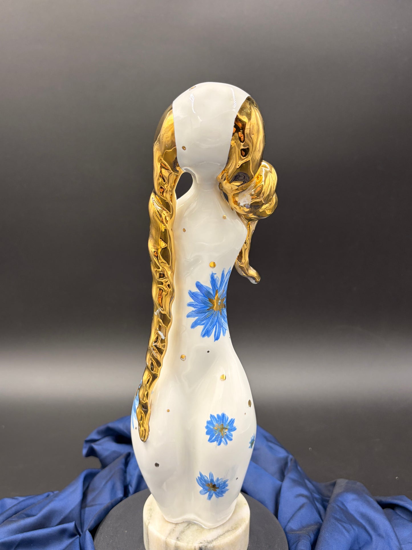 figurine with gold hair and blue flowers on a gray background