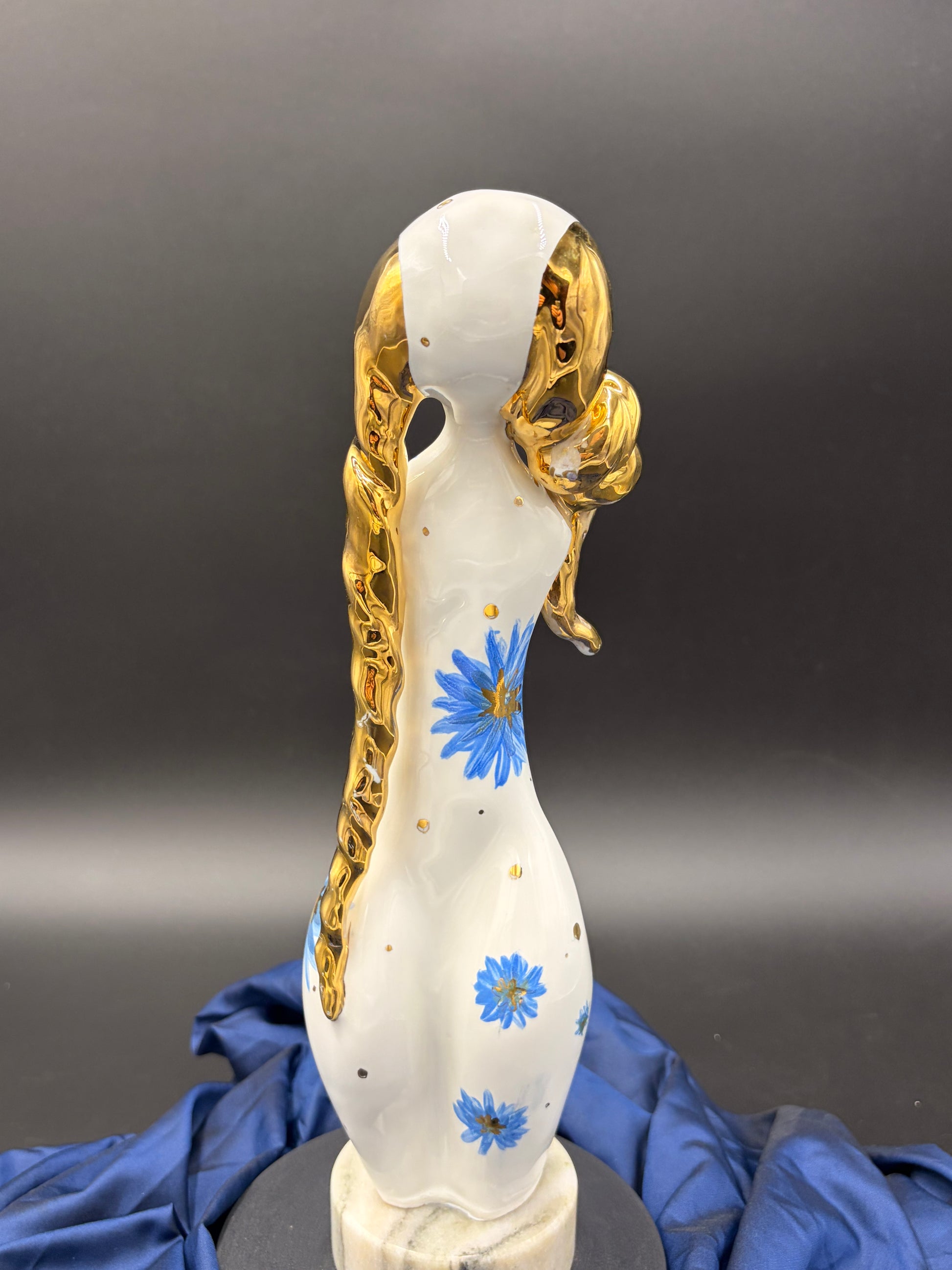 figurine with gold hair and blue flowers on a gray background