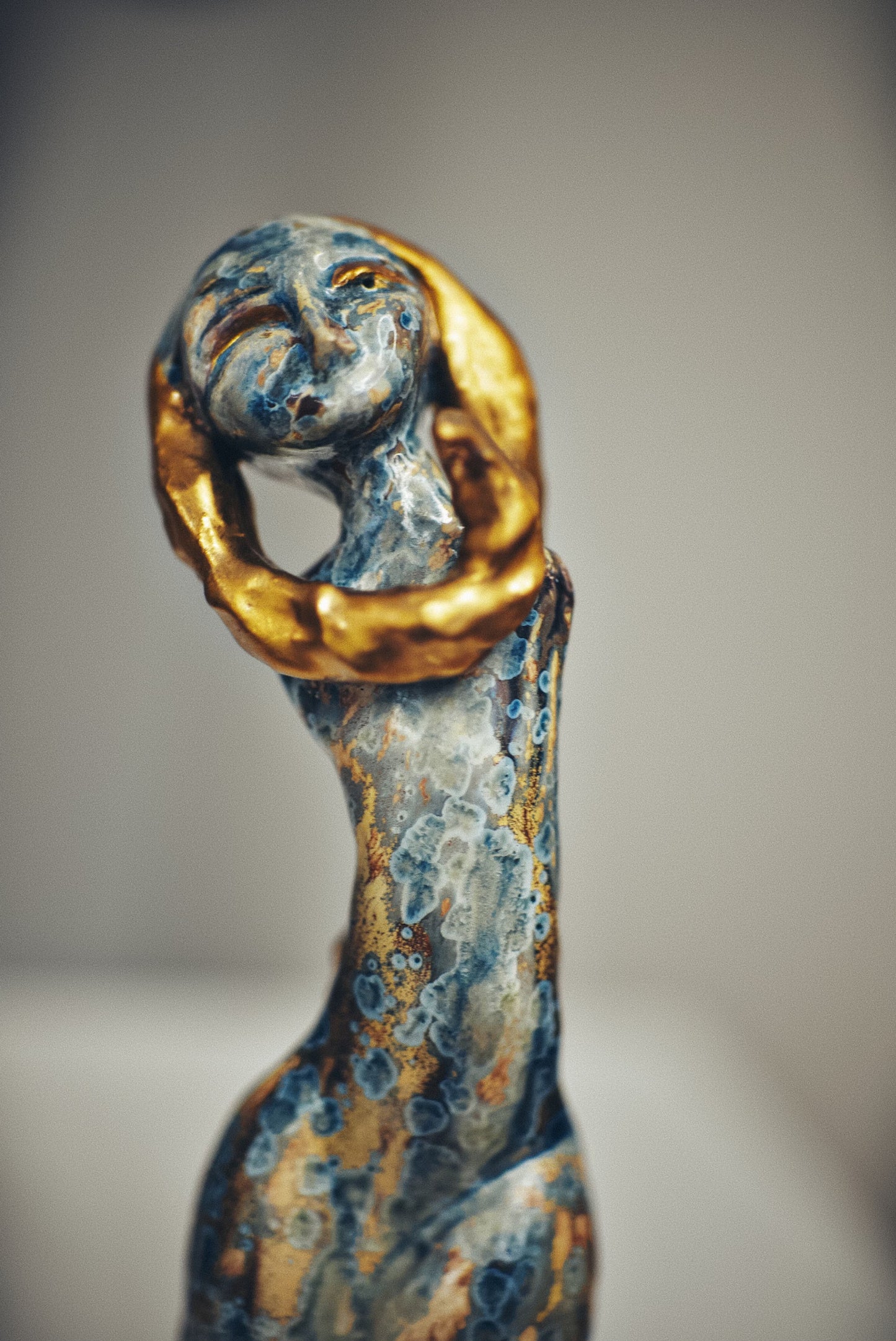 Decorative figurine with gold and blue finish on a neutral background