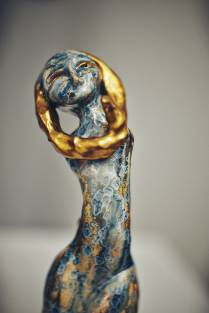 Decorative figurine with gold and blue finish on a neutral background