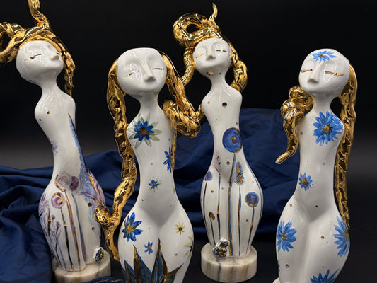Four ornate ceramic figurines with decorative designs on a dark background