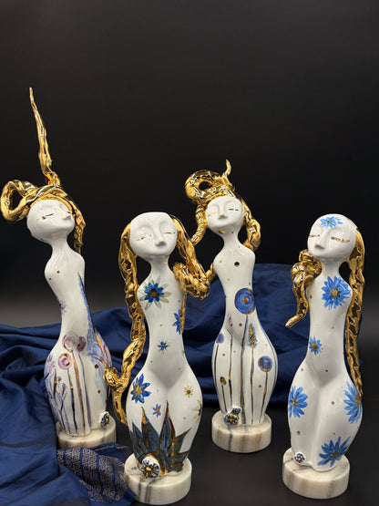 Four ceramic figurines with decorative designs on a dark background