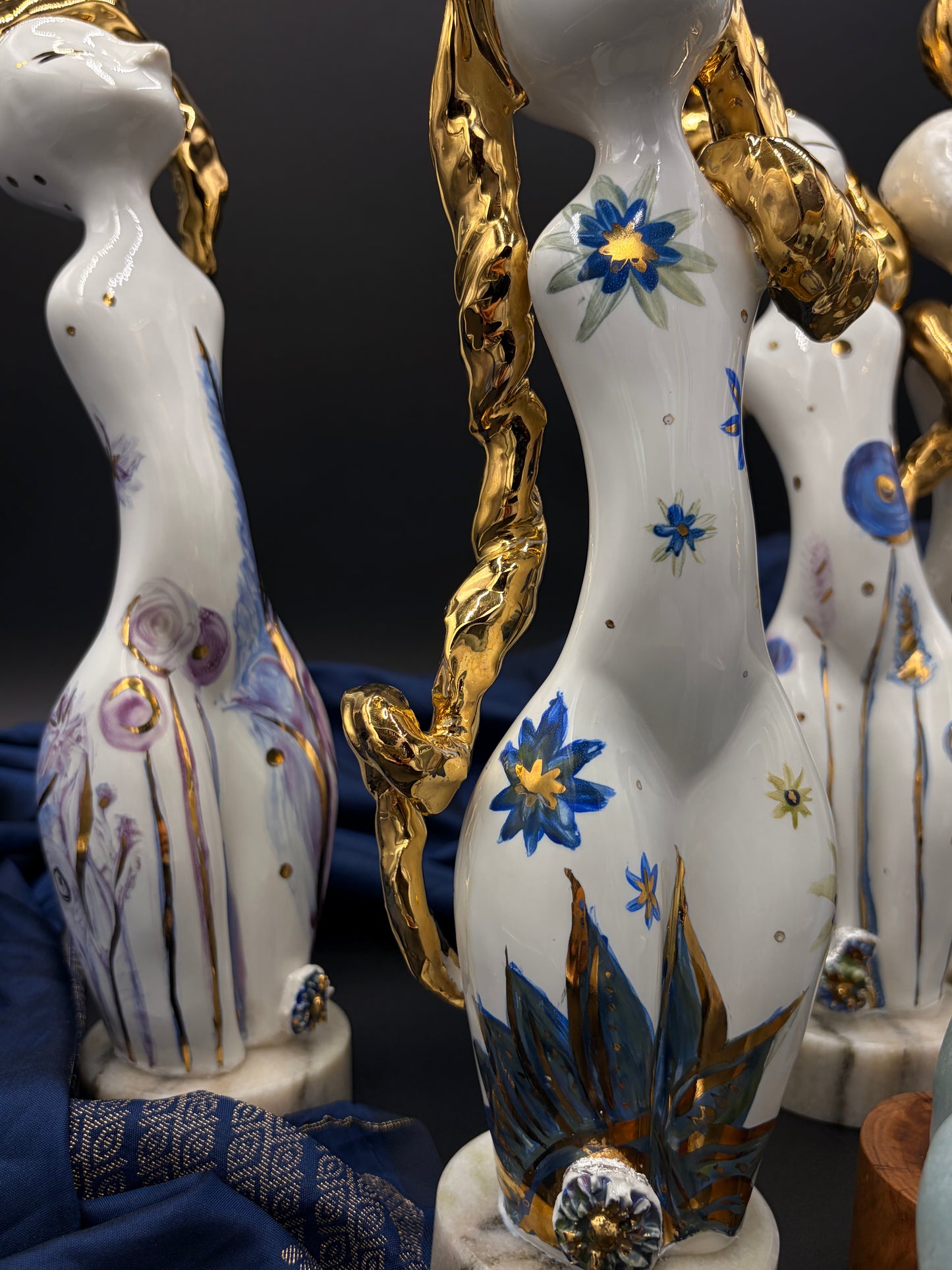 Decorative ceramic vases with floral designs and gold accents on a dark background