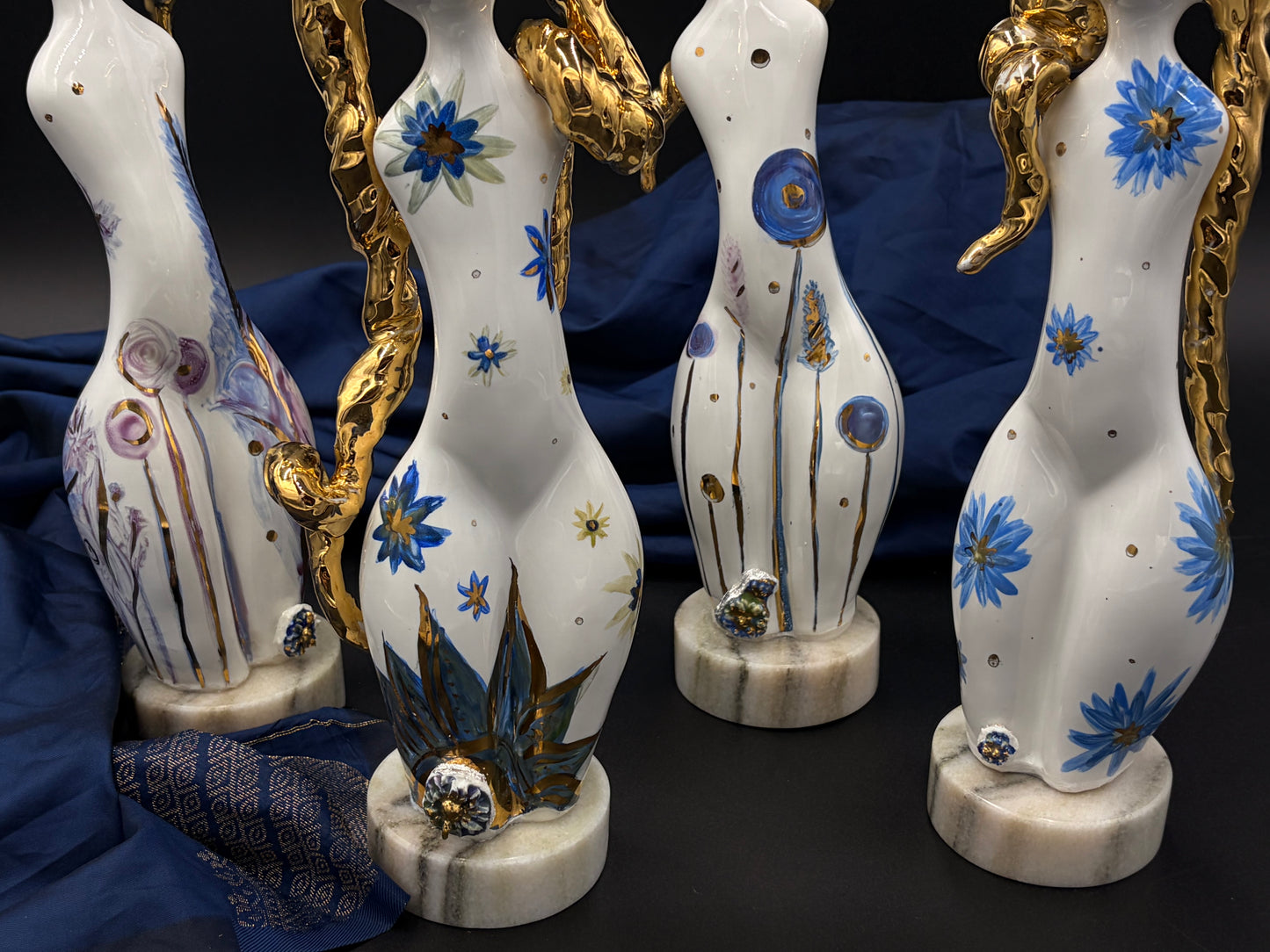 sculptures with floral designs and gold accents on a dark background