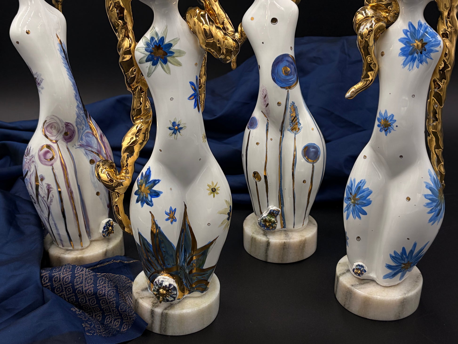 sculptures with floral designs and gold accents on a dark background