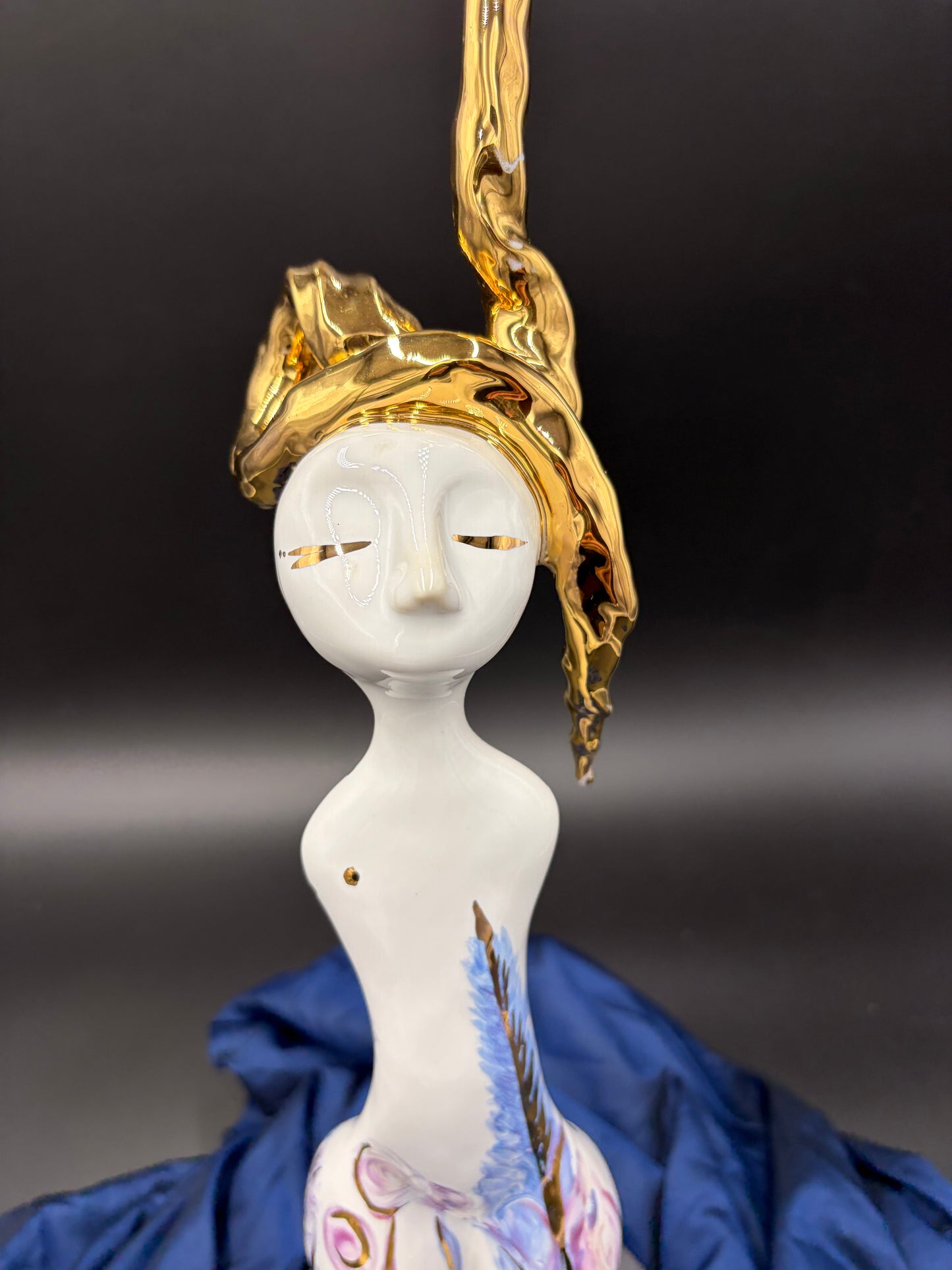 figurine with gold headpiece and white body against a dark background