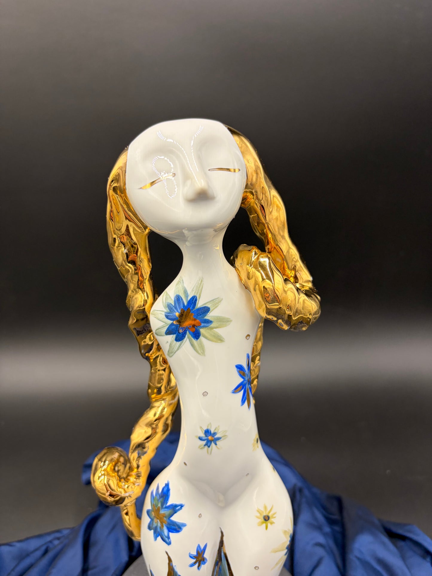 figurine with floral designs and gold hair on a dark background